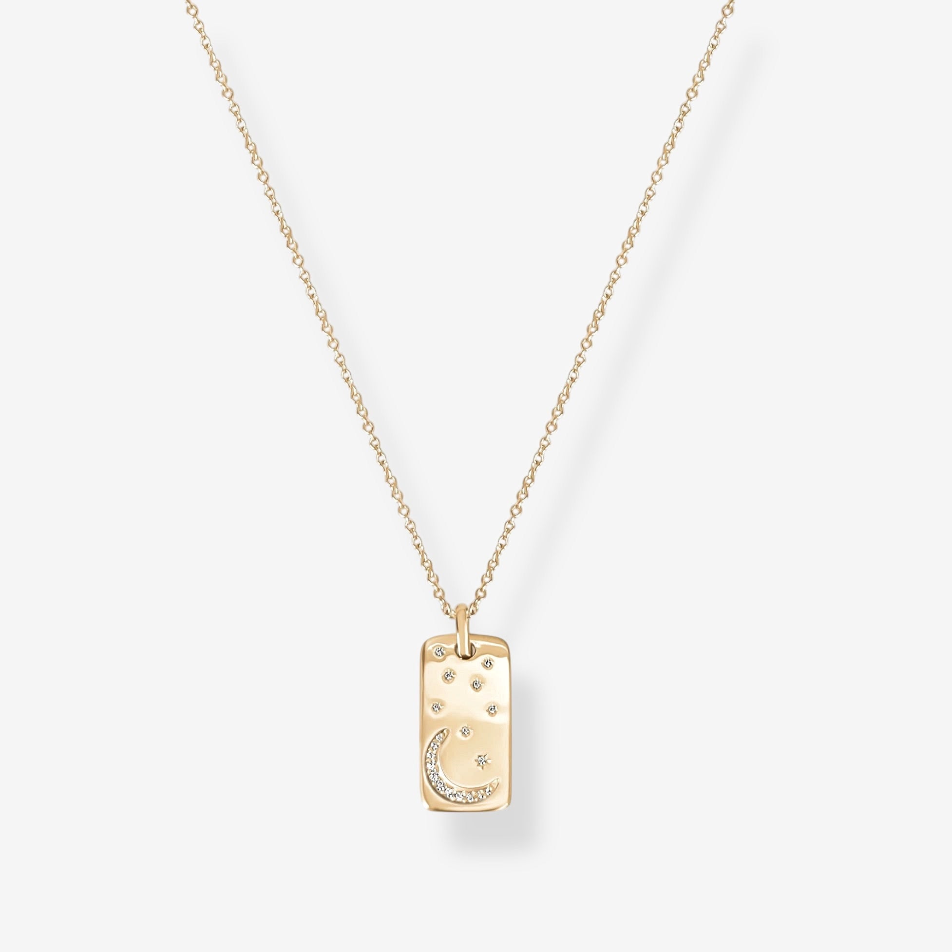 The Moonlight Pendant Necklace – Gold features a delicate gold chain with a rectangular pendant engraved with crescent moon and star designs, accented by small white stones, displayed on a plain white background.