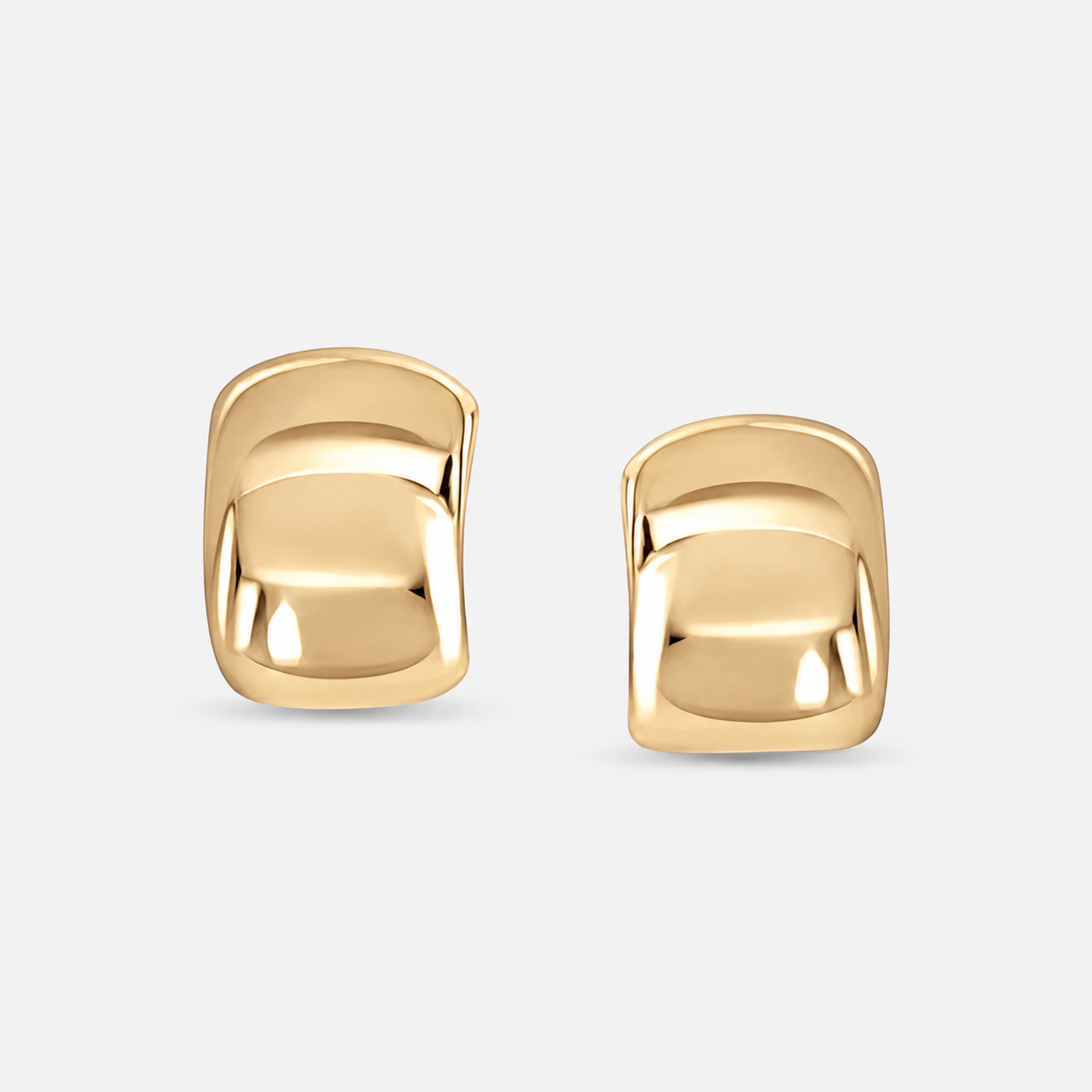 Close up of Brooke’s Curved Sculptural Earrings in polished 14k plated gold on light gray background