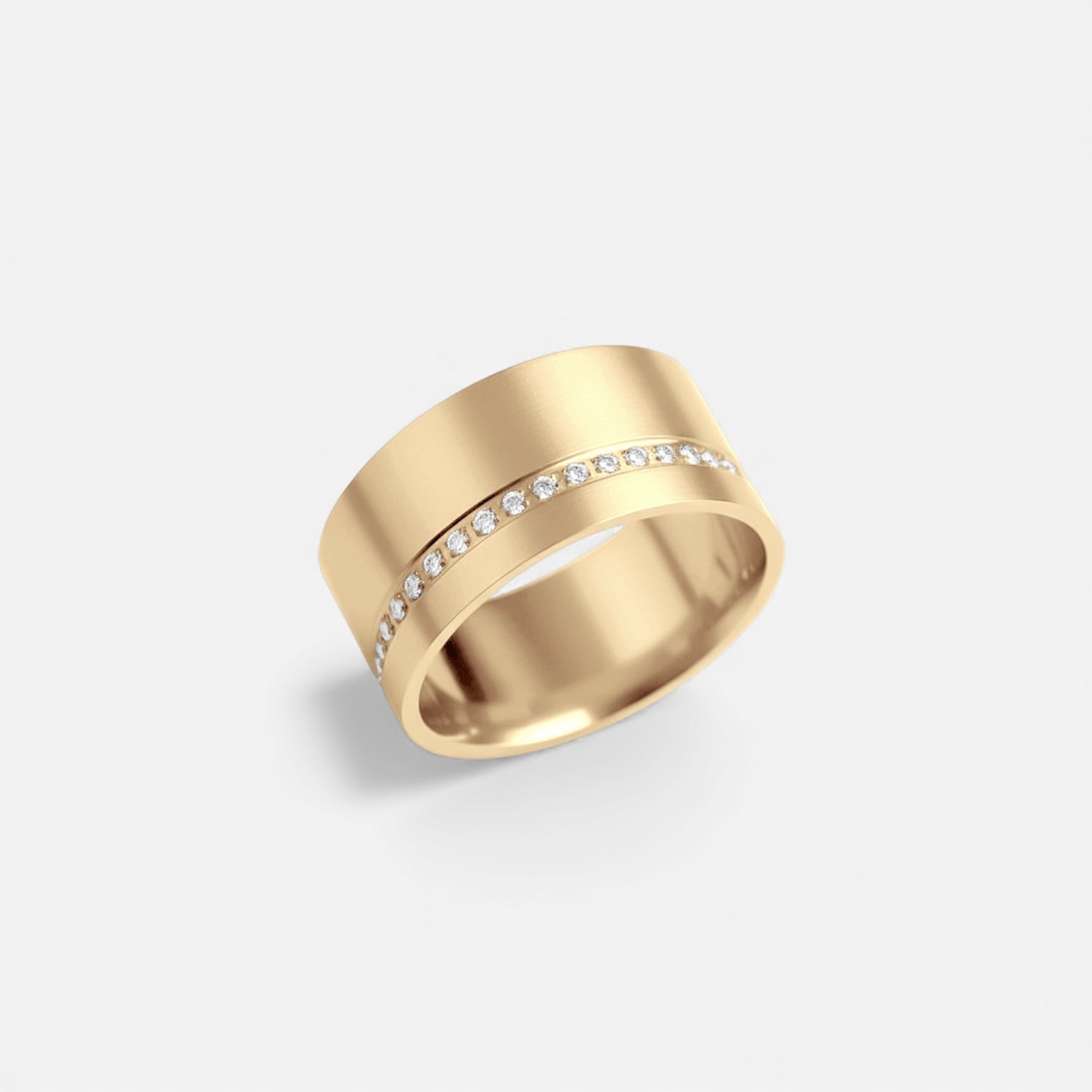 Celine cigar ring in gold featuring a wide polished band with a pavé diamond center row on a white background
