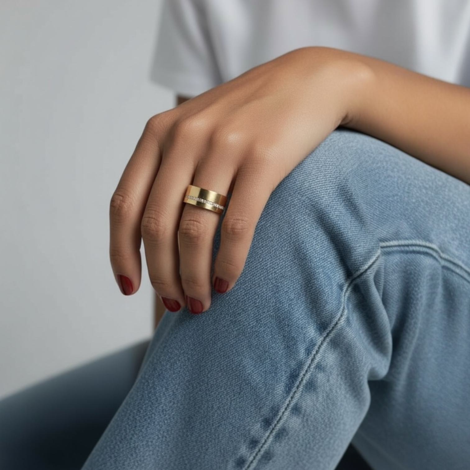 Celine cigar ring worn on a model’s hand showcasing the wide gold band with pavé detail styled casually with denim