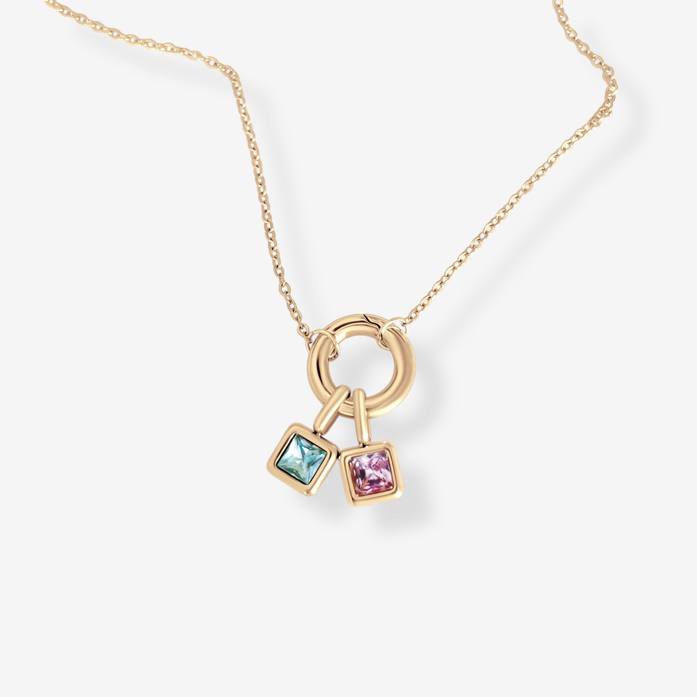 Gold birthstone necklace with two dainty gemstone charms styled in a flat lay on a minimalist background
