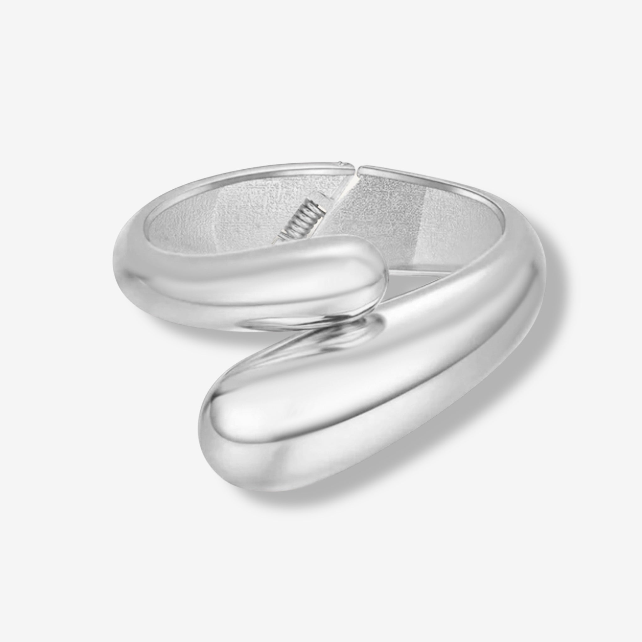 The Jade Snake Bangle is a modern, sculptural silver ring with an open-ended design and smooth, overlapping rounded ends that evoke the style of a statement bracelet.