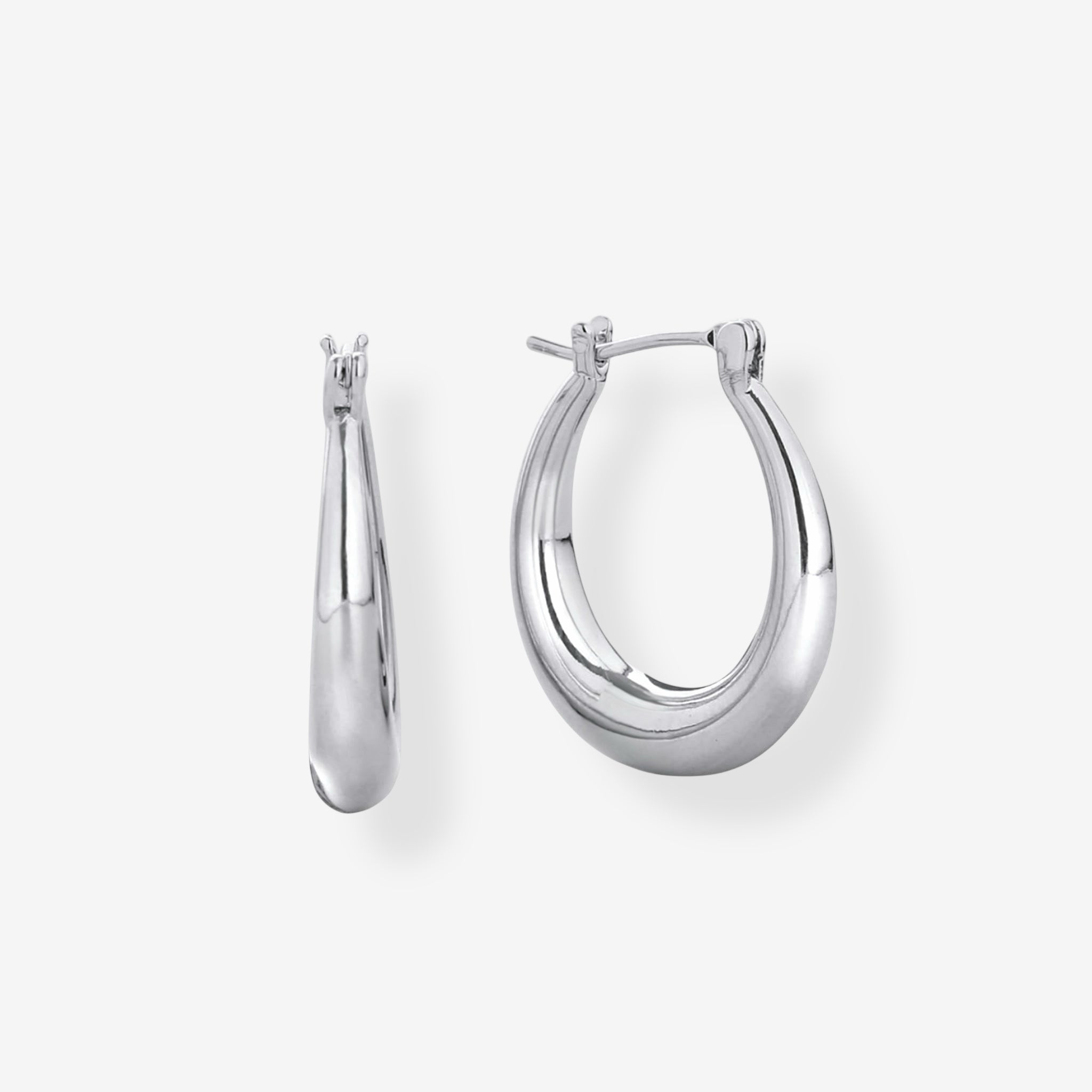A pair of Riley Oval Hoops in rhodium plated silver, featuring a polished, slightly tapered and rounded design. Displayed on a plain white background with one earring facing front and the other turned to the side.