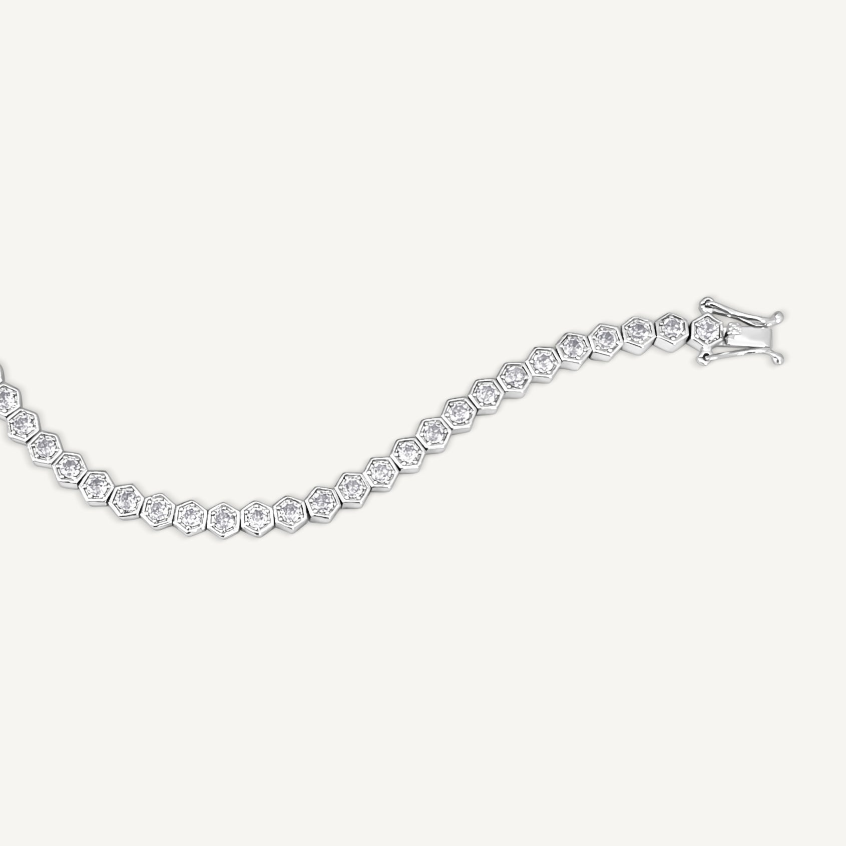 The Hexagon Tennis Bracelet, with silver hexagon links set with round simulated diamonds, is shown on a white background. The bracelet’s clasp appears on the right.