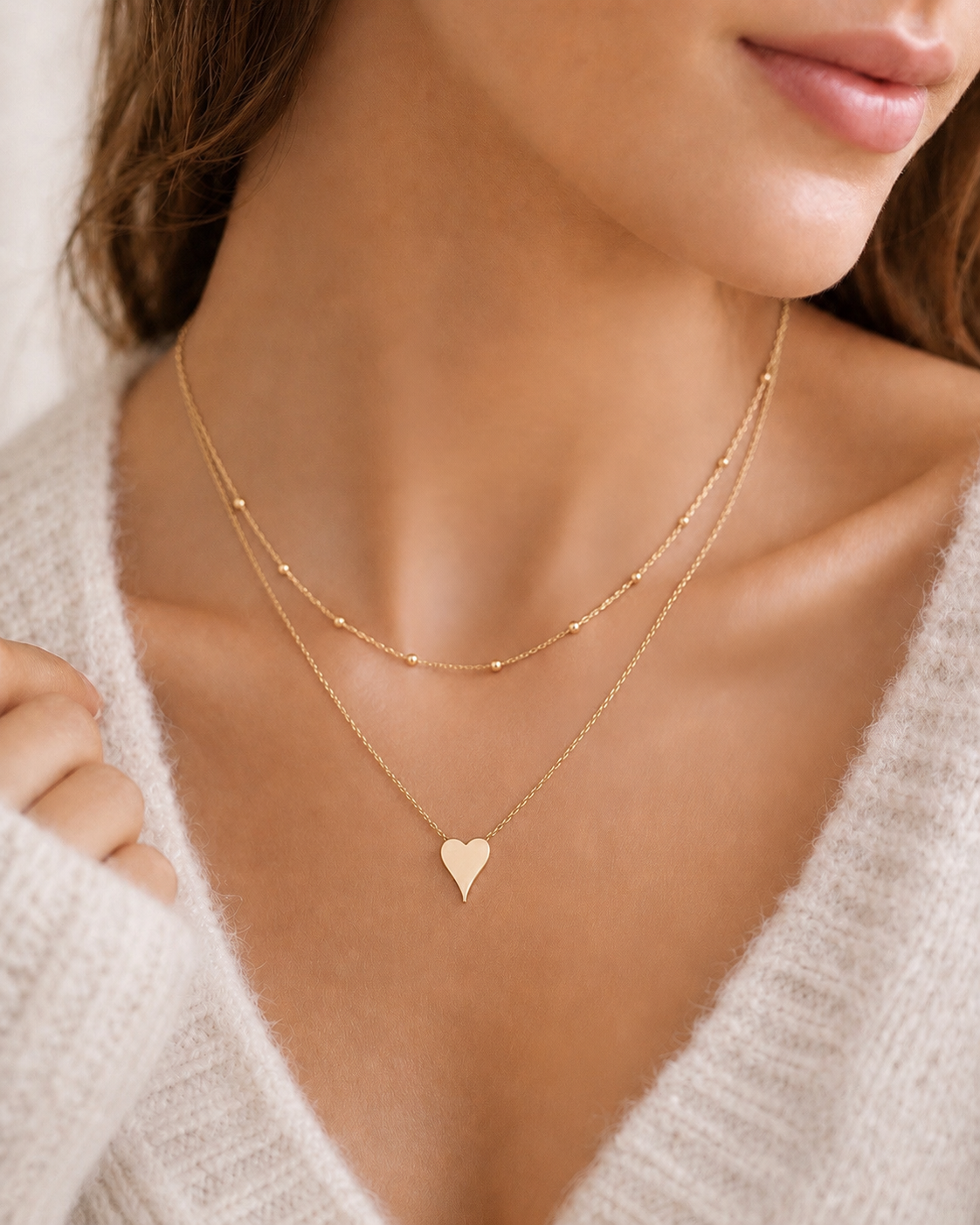 Model wearing layered gold necklaces featuring Terry heart pendant necklace with dainty chain styling