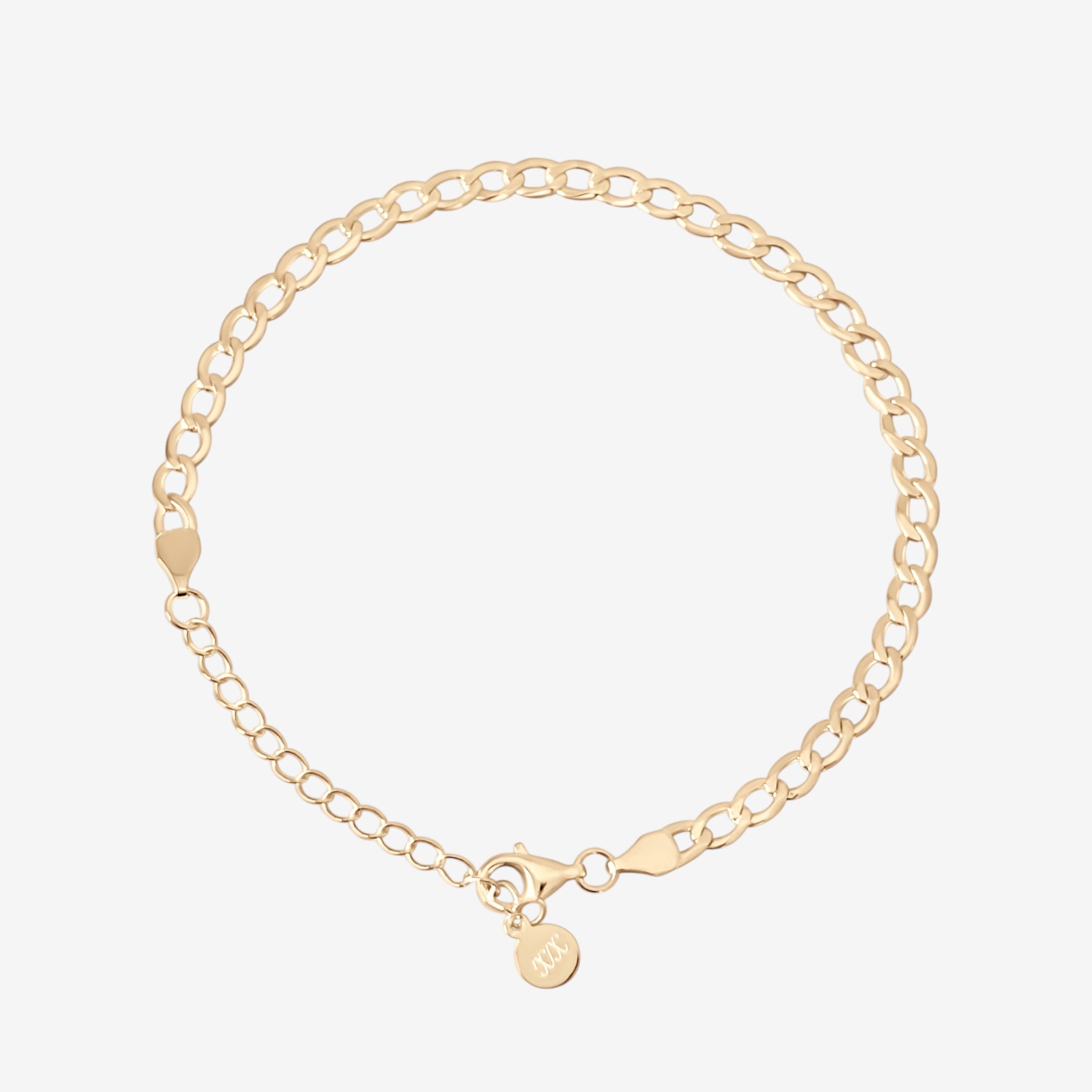 The Brynn Cuban Bracelet is a delicate 14k gold plated chain with a round charm by the clasp, elegantly shown against a white background.