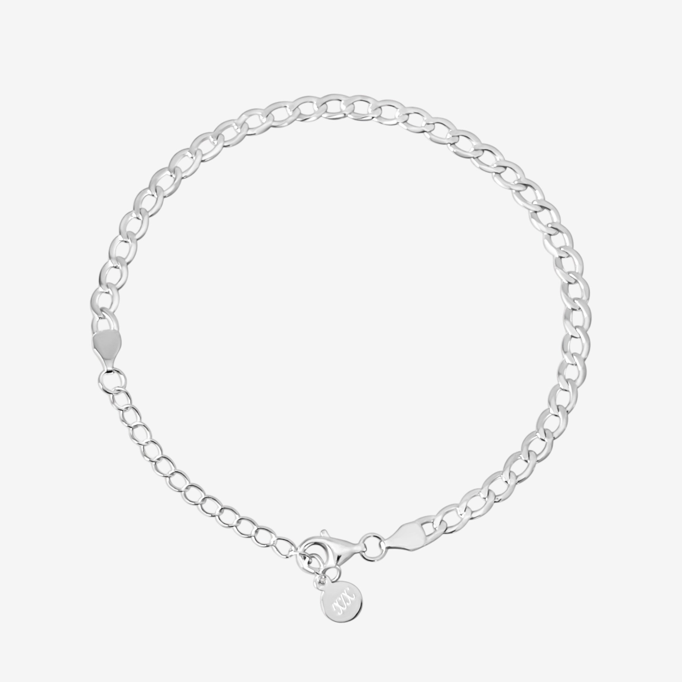 The Brynn Cuban Bracelet, crafted in sterling silver with oval links and a small round charm near the clasp, is showcased on a plain white background.