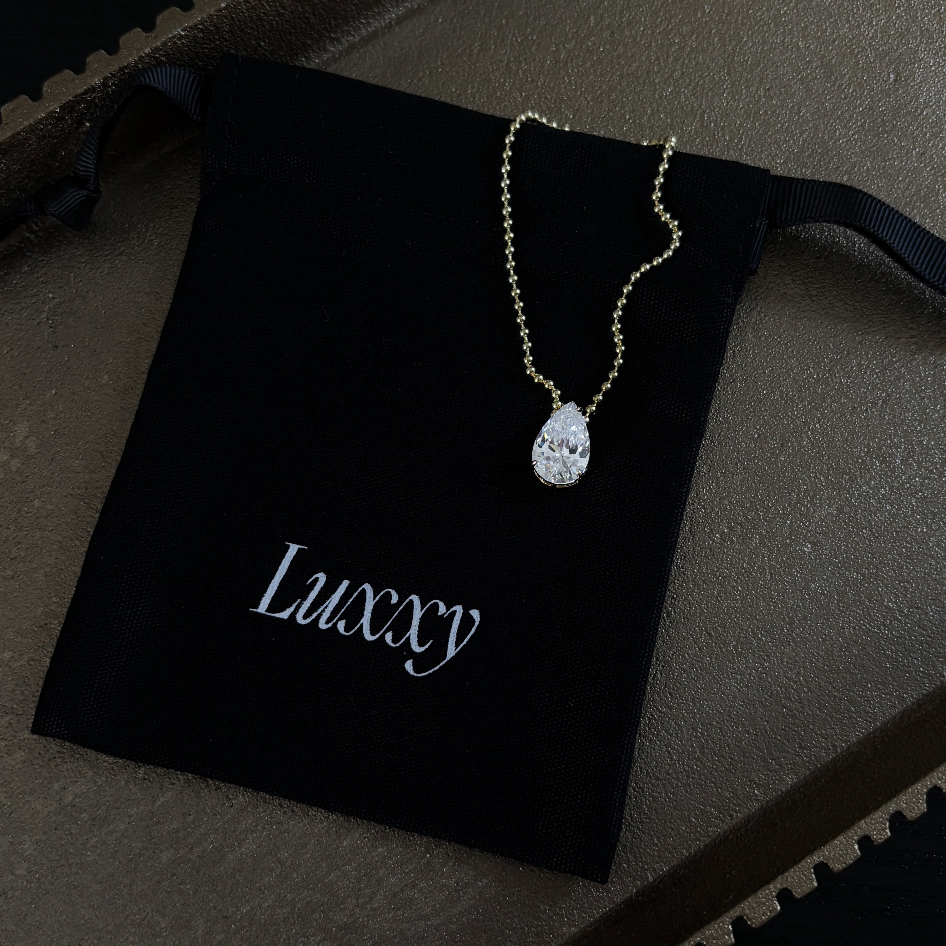 Ava Necklace in gold showing pear-shaped simulated diamond pendant and delicate bead ball chain with refined minimalist Luxxy style
