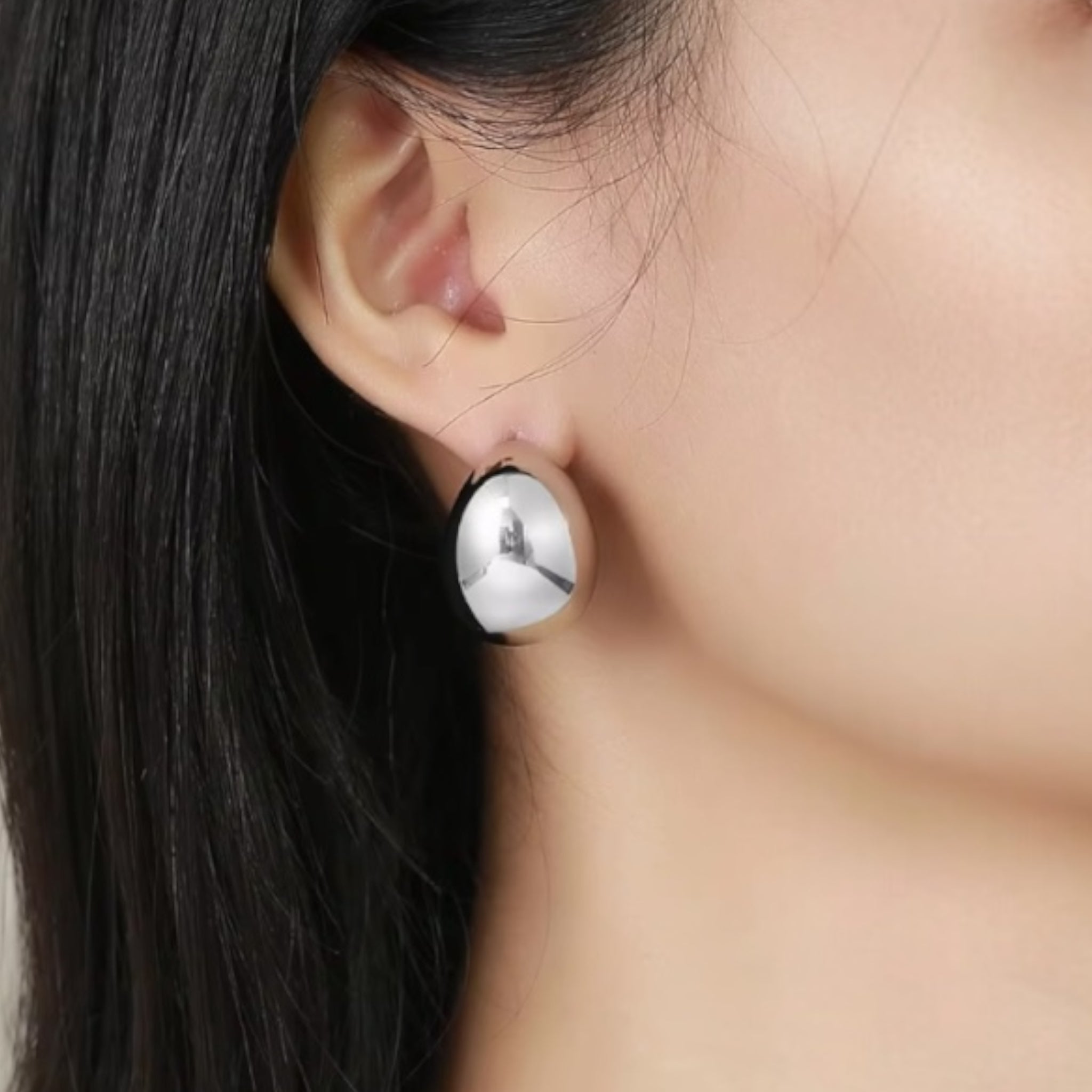 Close-up of model wearing Dani Crescent Earrings in silver showing sculptural crescent design and polished rhodium shine