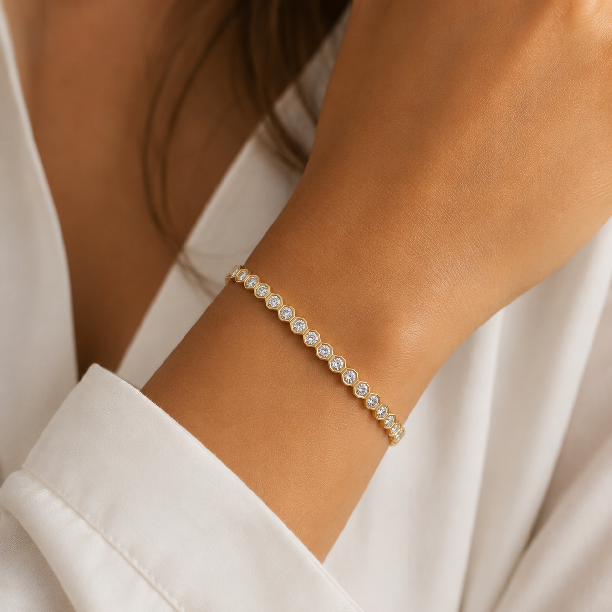 Close up of gold hexagon tennis bracelet layered on wrist with modern geometric CZ design