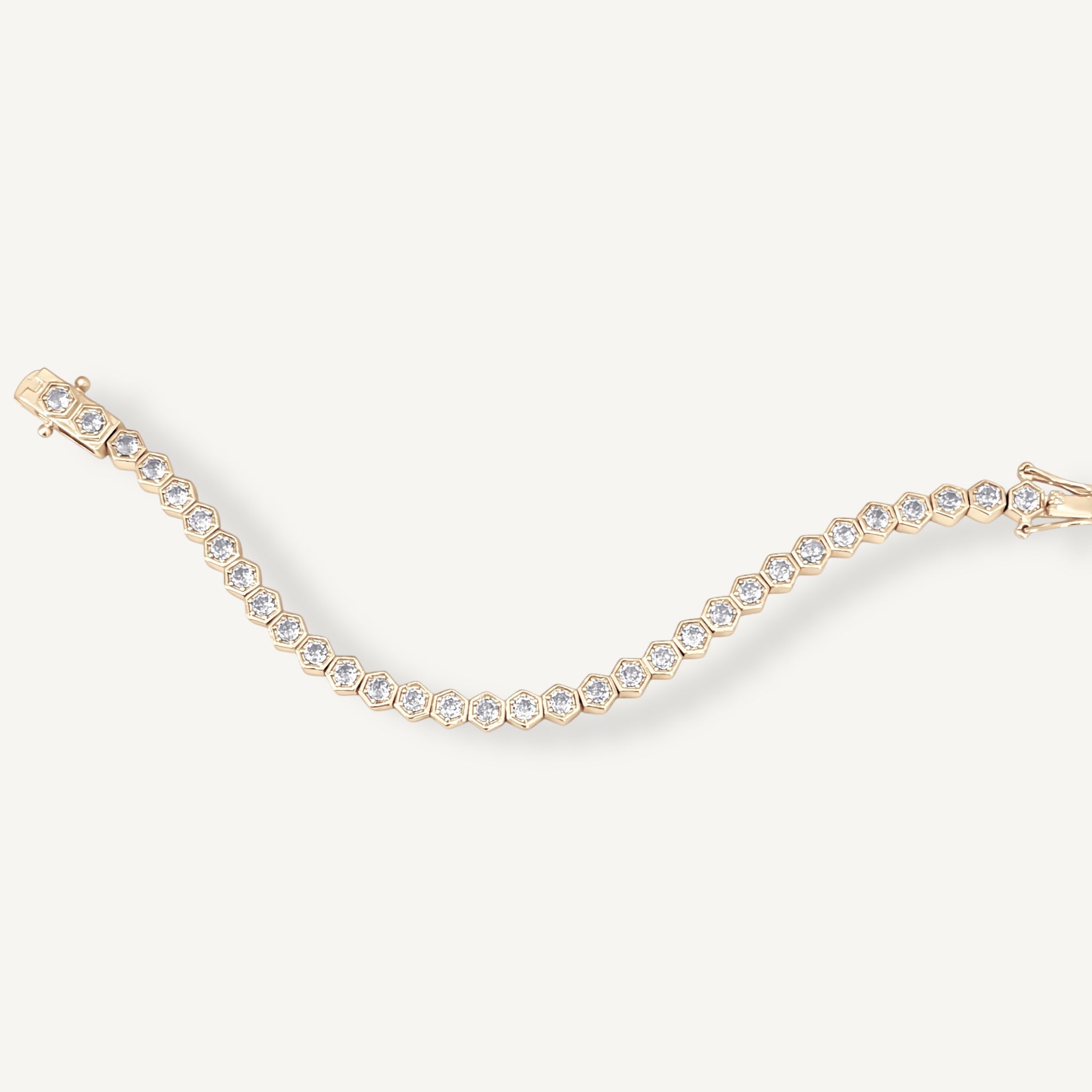 Gold hexagon tennis bracelet with bold geometric bezels displayed flat on surface