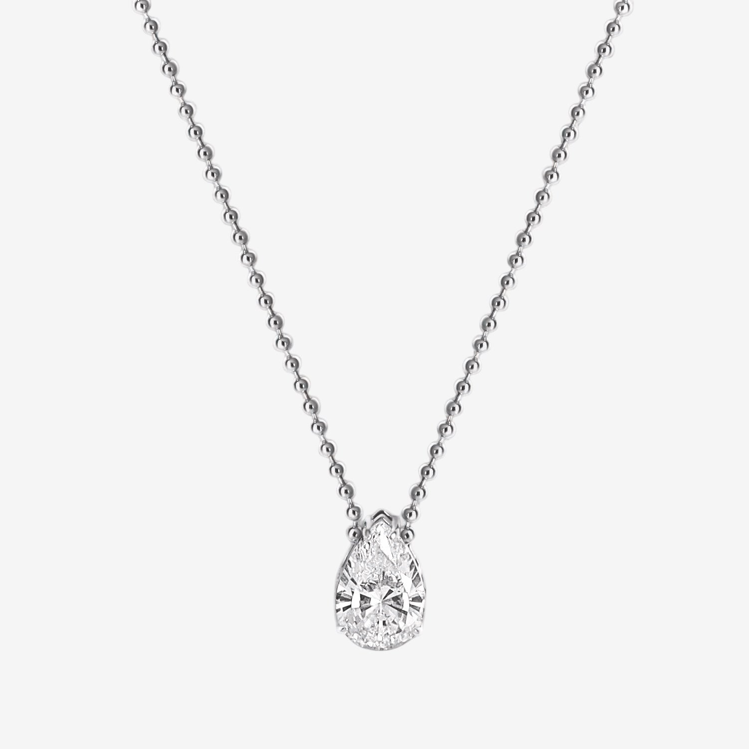 The Ava Necklace is a delicate sterling silver piece featuring a pear-shaped simulated diamond pendant on a fine beaded chain, shown against a plain white background.