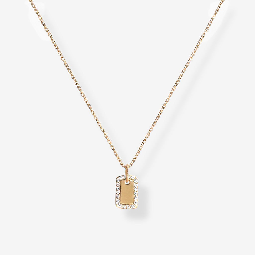 The Dainty Dog Tag Necklace is a delicate gold chain with a small rectangular pendant outlined in sparkling stones, shown on a plain white background.
