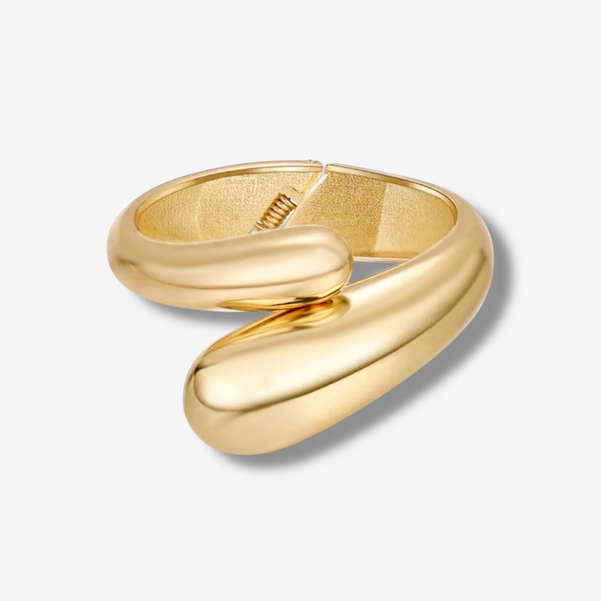 The Jade Snake Bangle features a smooth, modern gold design with overlapping rounded ends in an open spiral shape—perfect for pairing with your favorite accessories. Shown casting a soft shadow on a light gray background.
