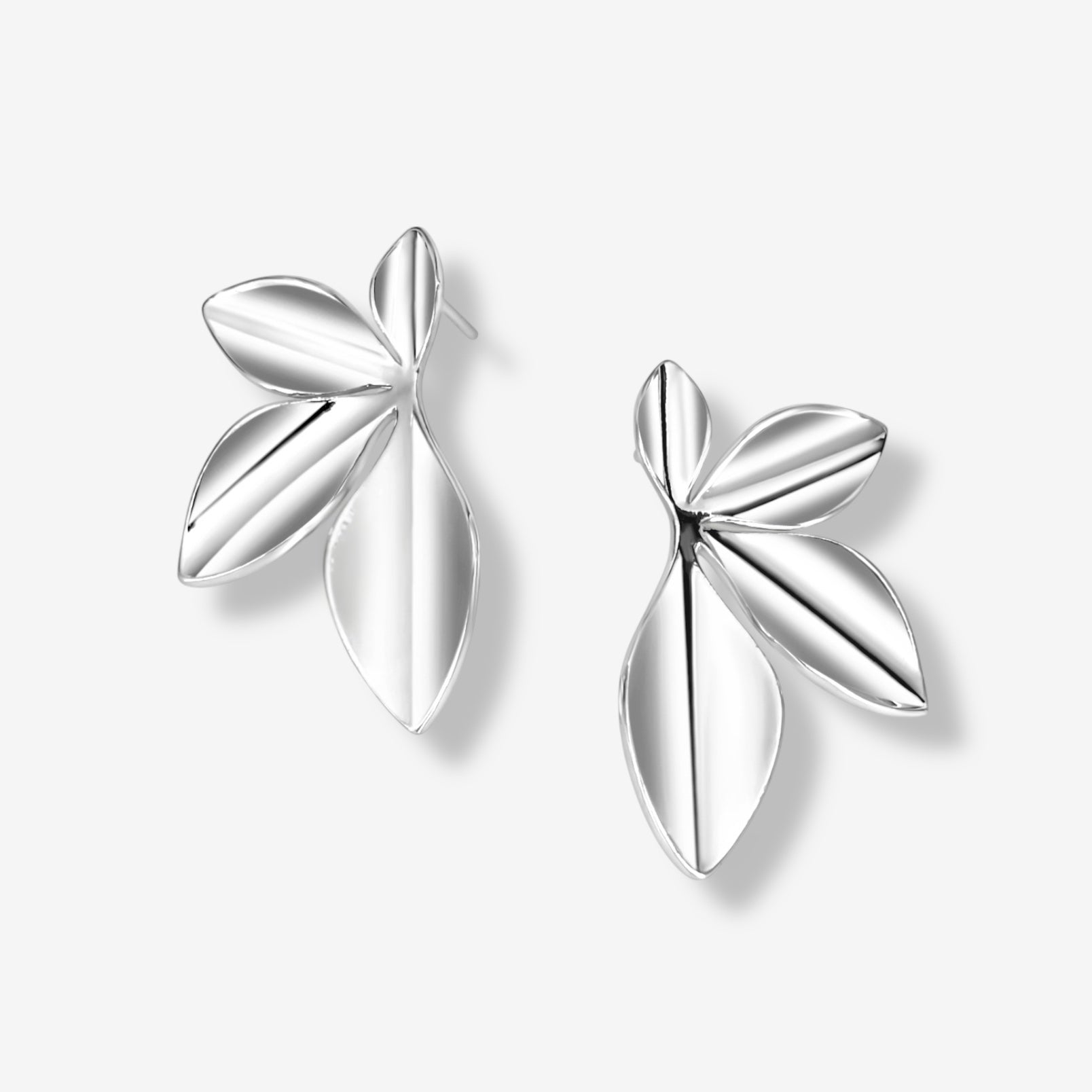 The Harper Statement Petal Earrings feature a shiny silver finish with three overlapping leaf-shaped petals, making them perfect as unique statement earrings. Displayed on a white background.