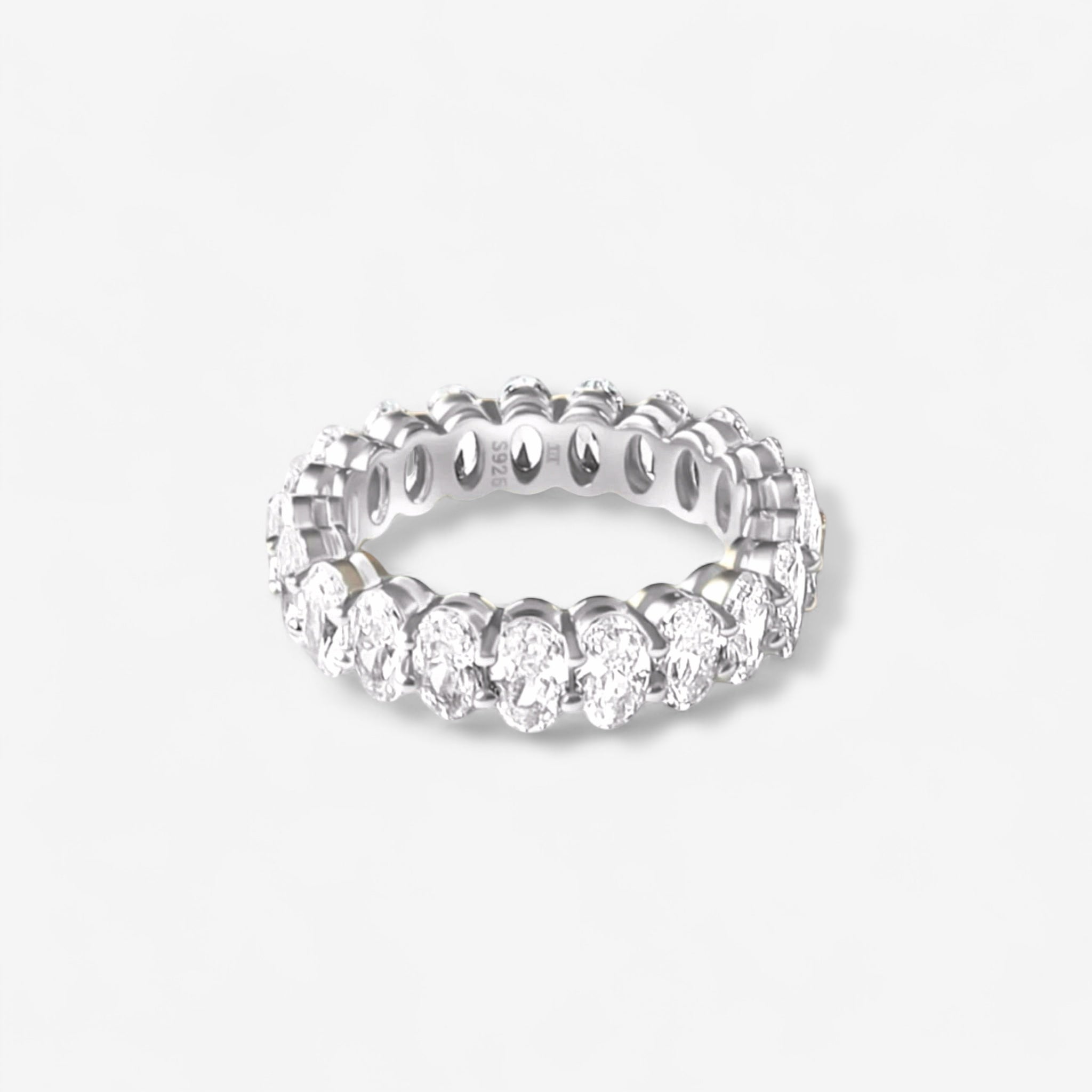 The Aria Ring is a sterling silver band adorned with oval-cut simulated diamonds in a prong setting, shown against a plain white background.