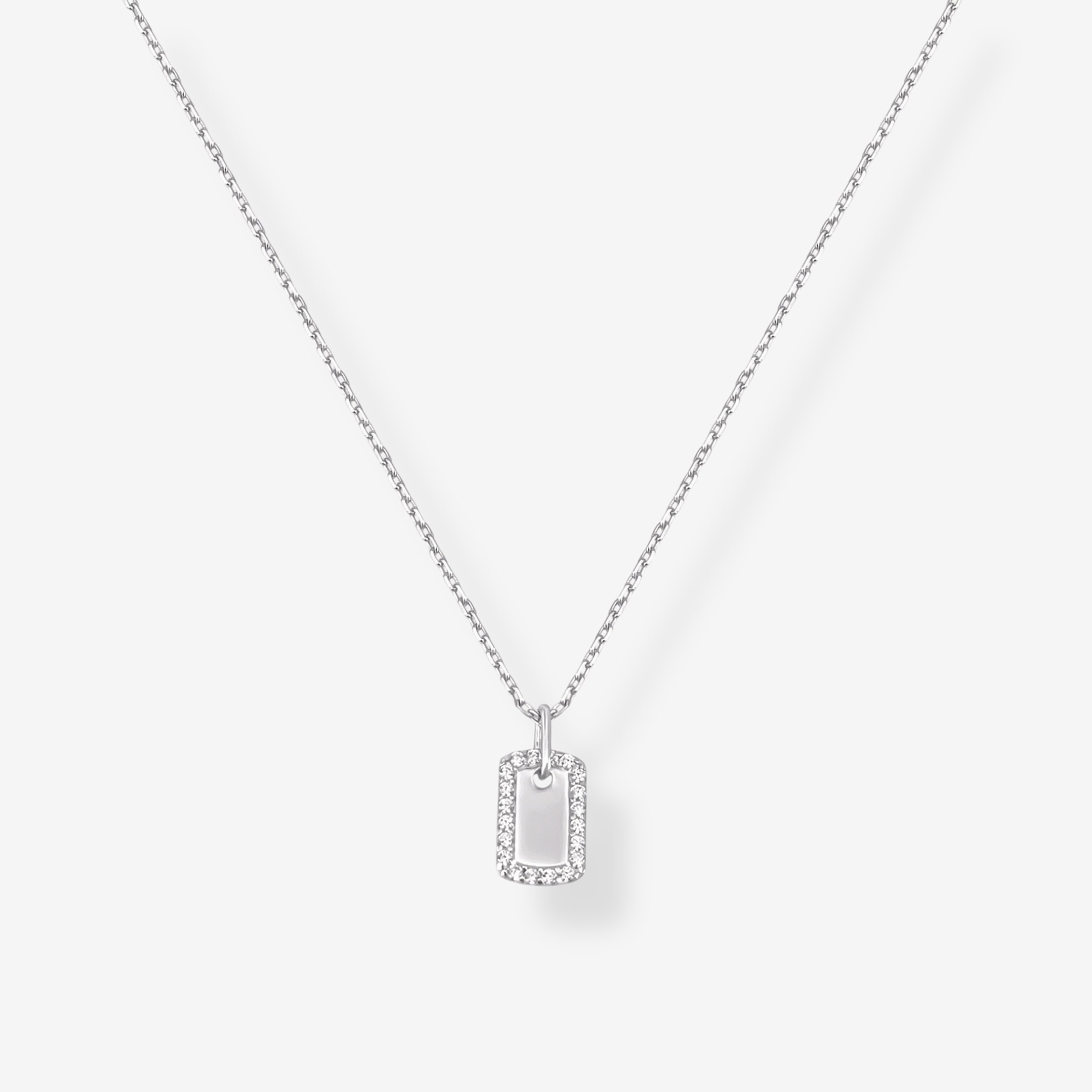 The Dainty Dog Tag Necklace features a delicate sterling silver chain with a small rectangular charm encrusted with sparkling white stones, shown against a plain white background.