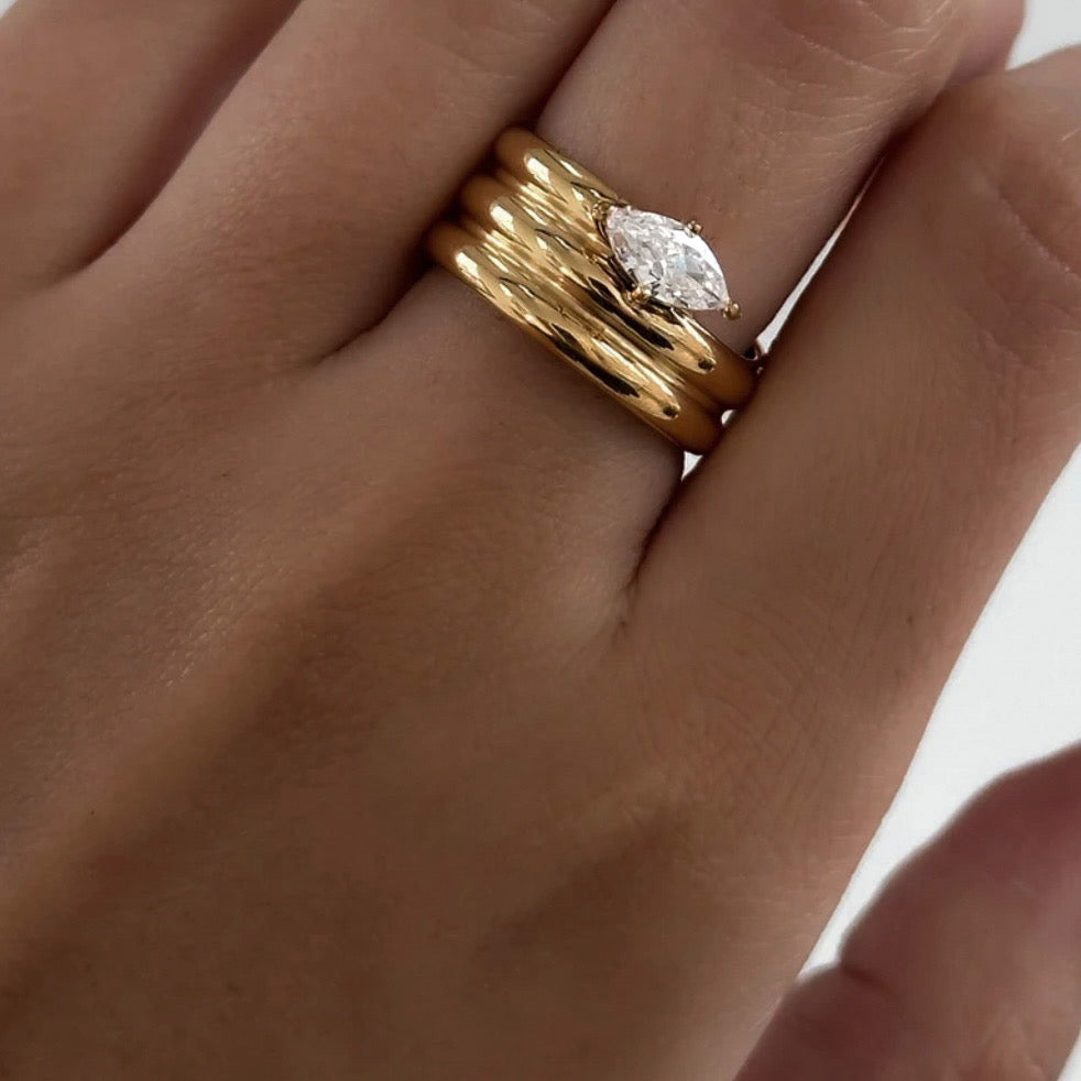 Close-up of the Melia Ring in gold worn on a model, featuring a stacked band design and marquise-cut center stone