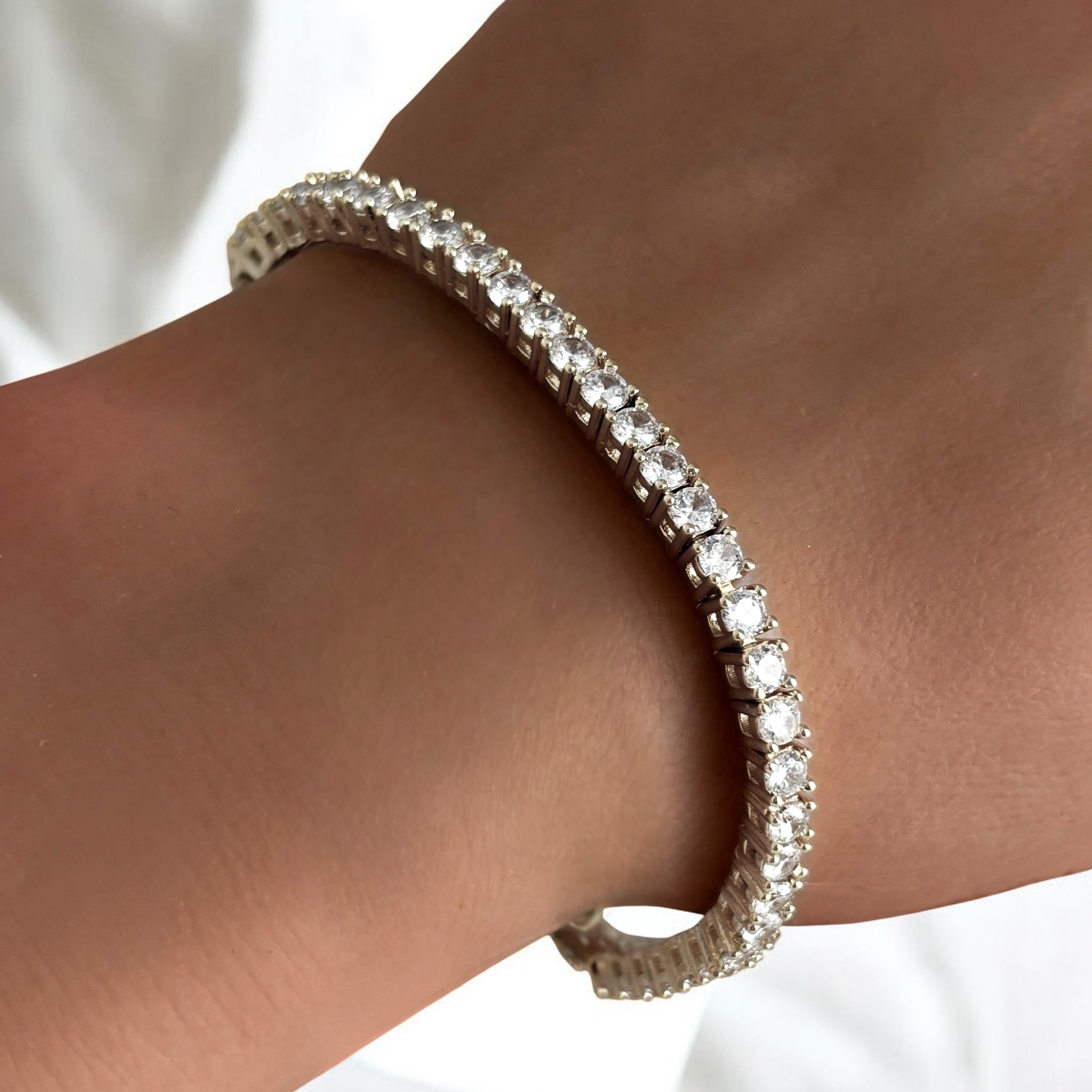 Close up of model’s wrist wearing Mia Tennis Bracelet in silver showing brilliant simulated diamond row and polished rhodium shine for modern sophistication