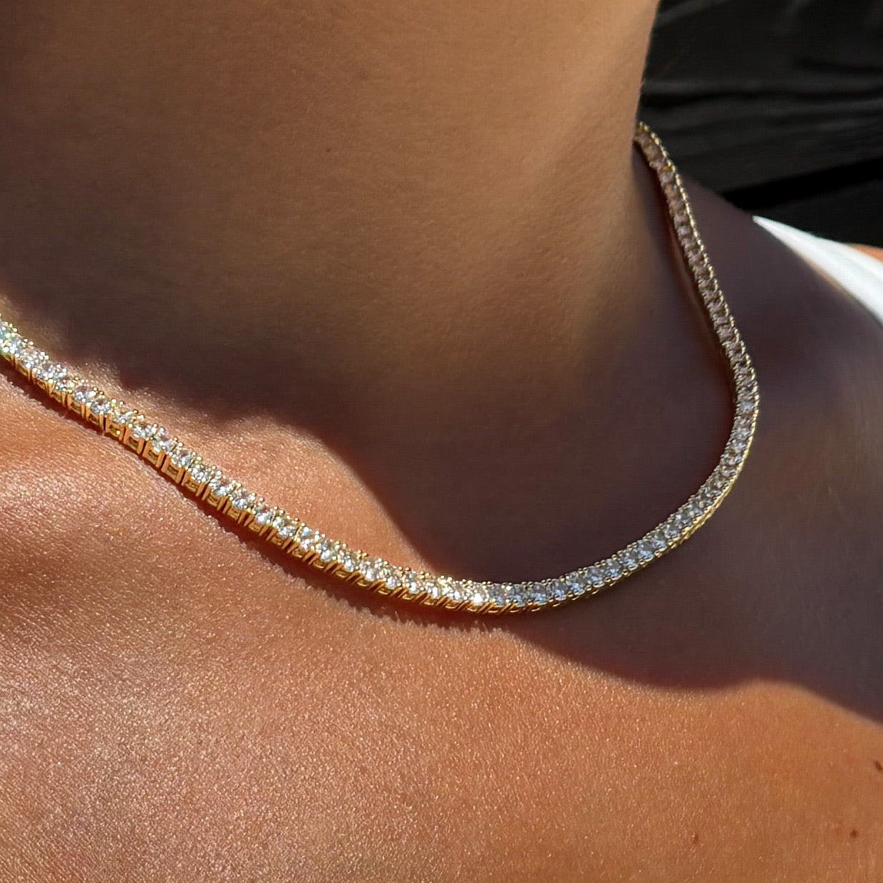 Model wearing Mia Tennis Necklace in gold showing radiant simulated diamond chain with 14k gold plated finish styled for modern, elegant Luxxy style