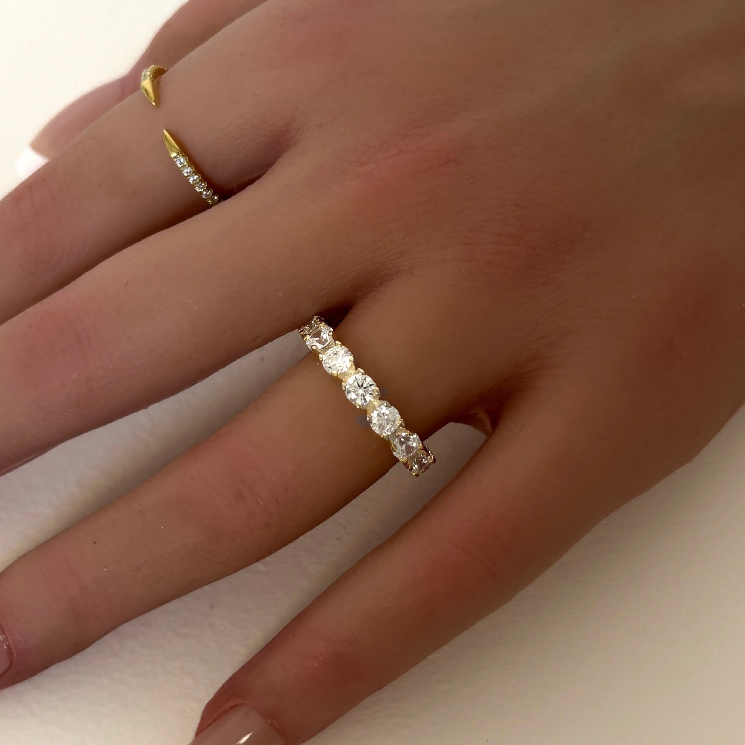 Model’s hand wearing Sydney Ring in gold showing row of round simulated diamonds with radiant gold finish for refined sparkle and everyday elegance